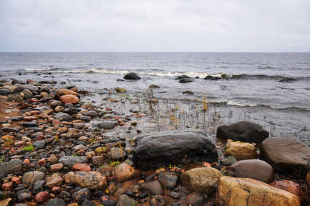 Stones on the shore of stormy waving Ladoga lake. Priozersk, Russia.の写真素材