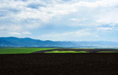 Rural landscape, plowed field, mountain ridge at the horizon. Altai, Russia.の写真素材