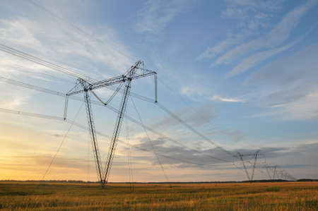 High voltage power line in the field against beautiful clouds in the sky