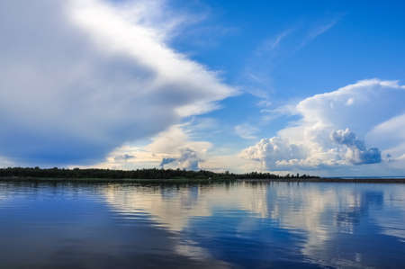 Blue sky with Cumulus clouds over the forest at the Lake Ladoga shore.の写真素材