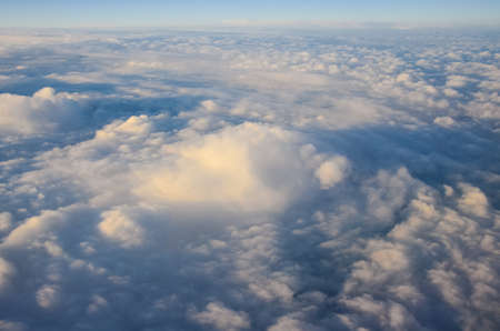 Airplane flying above clouds at sunrise. Aerial window view.