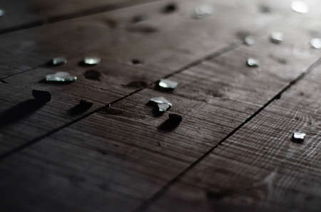 Small shards of glass on the dark wooden floor.の写真素材