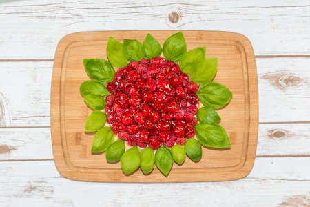Juicy raspberry cake decorated with basil leaves on a wooden boardの写真素材