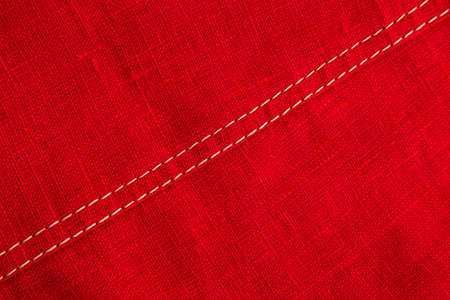 finishing stitch, double seam, made with beige threads in a product made of red linen fabricの写真素材