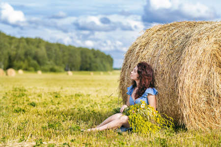 a young woman with a large bouquet on a summer day in a mown fieldの写真素材