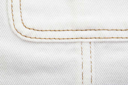 white denim fabric, connecting parts with various seams with brown threads, raw edge with fringe