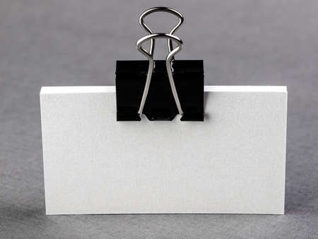 pack of paper blanks for business cards with a metal clip on a light background, isolateの写真素材