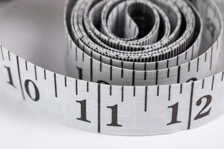 centimeter measuring tape with inches rolled up on a white background, isolateの写真素材