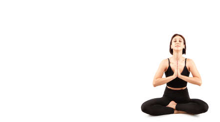 young beautiful woman in black leggings and top doing fitness indoors, on a white background, isolateの写真素材