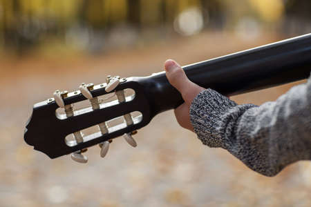 a teenage street musician plays a black acoustic guitar on an autumn day in the Parkの写真素材