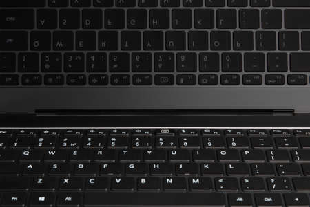 fragments and buttons of a black and silver laptop with white letters