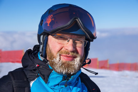 adult bearded man in ski suit, helmet and maskの写真素材