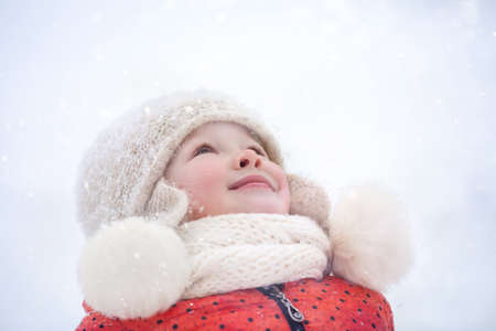 a little girl in a fluffy hat walks on a snowy winter dayの写真素材