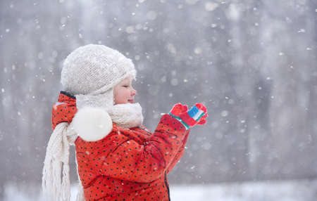 a little girl in a fluffy hat walks on a snowy winter dayの写真素材