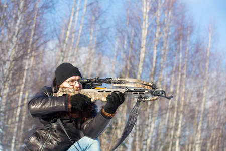 a man of European appearance in the winter forest shoots from a sports crossbowの写真素材