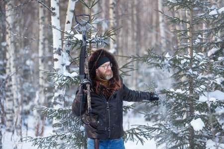 a man of European appearance in the winter forest shoots from a sports crossbowの写真素材