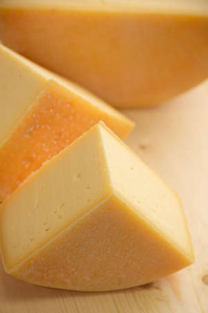 cheese of different varieties on a natural wooden background, whole and sliced