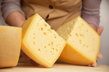 cheese of different varieties on a natural wooden background, whole and slicedの写真素材