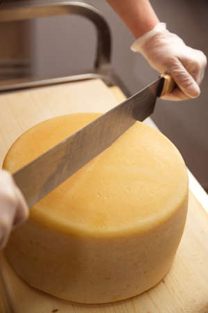 cheese of different varieties on a natural wooden background, whole and slicedの写真素材
