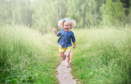 a girl with curly blonde hair walks in a meadow, a summer dayの写真素材