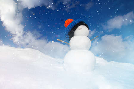 Christmas background, a snowman in a hat stands on a snowdriftの写真素材