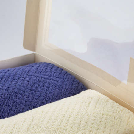 A set of two cotton terry towels in a paper box on a light background
