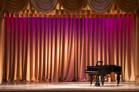 illuminated by lights stage with backstage and decorative columns, there is an old grand pianoの写真素材