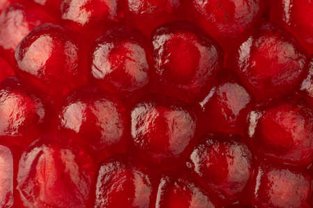 ripe pomegranate seeds, sweet fruit, red backgroundの写真素材