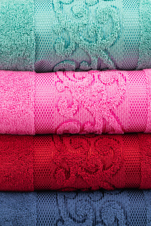 multicolored terry towels, rolled up and stacked on the tableの写真素材