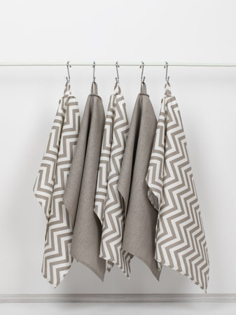 cotton waffle towels for the kitchen hang on hooks on a bracket against a white wall backgroundの写真素材