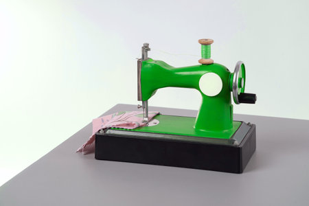 Children's small chain stitch sewing machine with manual drive is on the desktop