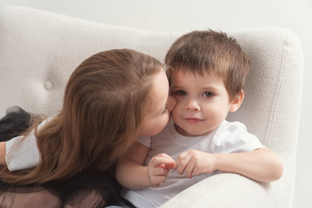 children a boy and a girl are sitting in an armchair in the studio, familyの写真素材