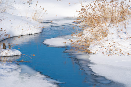 spring landscape with a river under ice and snowdrifts on the shore, Marchの写真素材