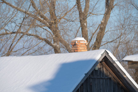 old brick chimney of a factory boiler room with smoke on a blue sky backgroundの写真素材