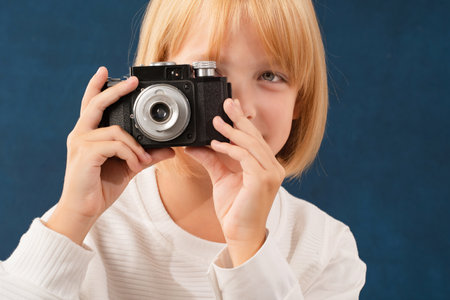 A blonde girl is photographed for a school album in a studio with a movie cameraの写真素材