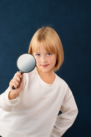 A blonde girl is photographed for a school album in a studio.