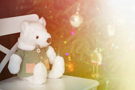 a stuffed toy, a teddy bear in a corduroy jacket, sits on a chair by the Christmas treeの写真素材