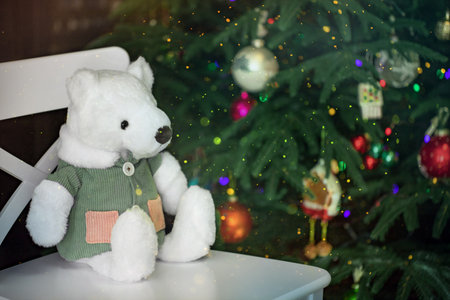a stuffed toy, a teddy bear in a corduroy jacket, sits on a chair by the Christmas treeの写真素材