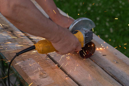 A man saws an iron pipe with a hand-held circular saw