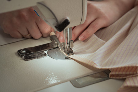A seamstress works on a production sewing machine at an enterprise, sewing bed linen