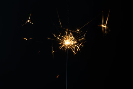 a match ignites a sparkler, fireworks on a black background