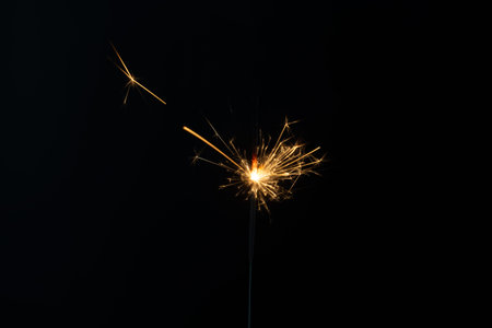 a match ignites a sparkler, fireworks on a black background