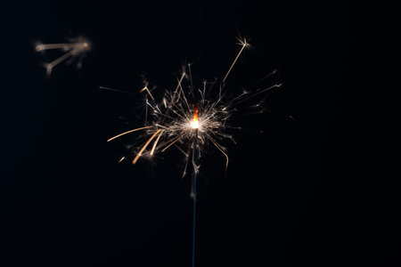 a match ignites a sparkler, fireworks on a black background