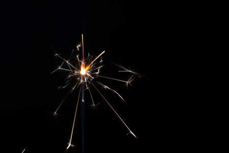 a match ignites a sparkler on a black background