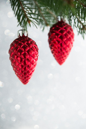 Red christmas ornaments (cones) on the xmas tree on glitter bokeh background. Merry christmas card. Winter holidays. Xmas theme. Happy New Year.の写真素材
