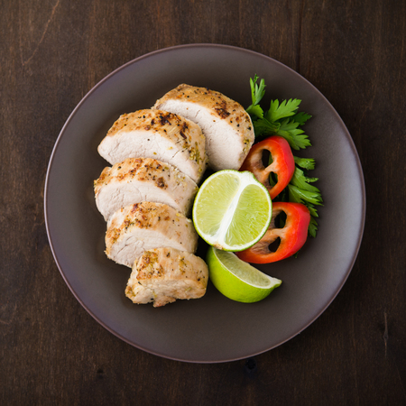 Sliced lime pork tenderloin with vegetables salad on dark wooden background top view.の写真素材