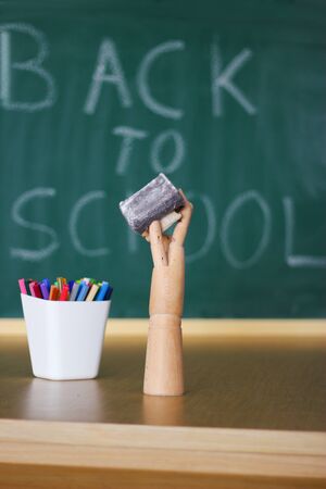 wooden hand holding eraser from chalkboardの写真素材