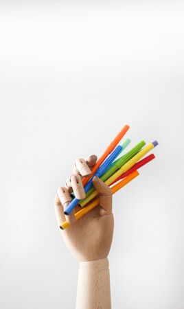 Articulated wood hand holding markers on white backgroundの写真素材