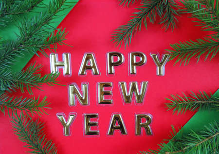 Happy New Year  gold letters on a red green background and natural fir branches of a Christmas tree    Happy New Year Concept. Flat Lay.の写真素材