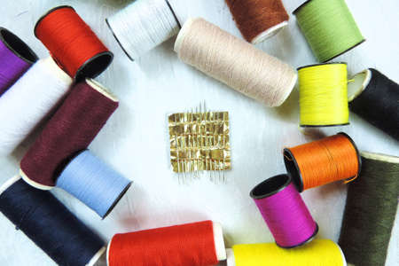 Composition with tailor needles and threads over white background